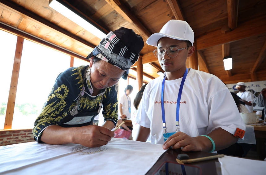 7月21日，手工藝人向留學生示范苗族蠟染繪畫技藝。