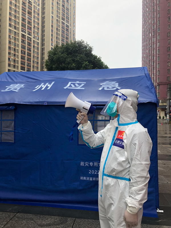 李剛在執勤點用喇叭向樓上居民進行防疫提示。貴陽市公安局云巖分局供圖