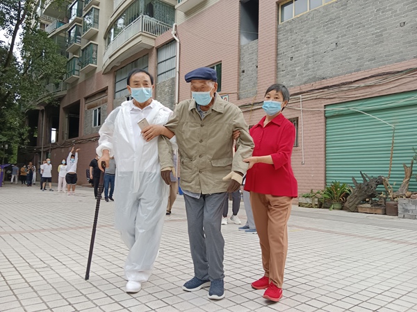 5 圖為陳進敏攙扶腳腿不便鄰居采集核酸（左一）。