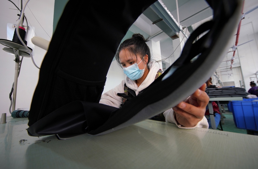 10月11日，工人在移民安置社區“幫扶車間”加工背包。