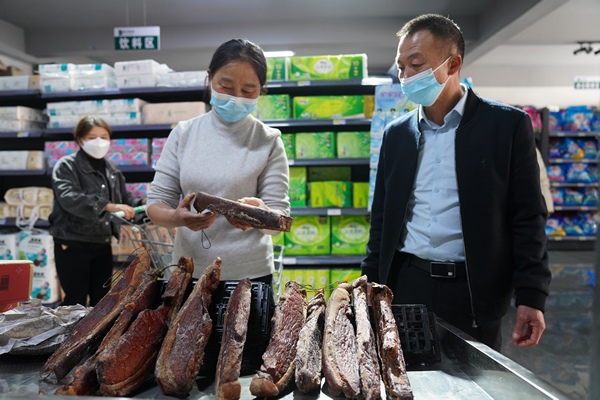 貴州省遵義市泥高鎮泥高社區居民在泥高鄉村振興服務站便民超市選購臘肉。