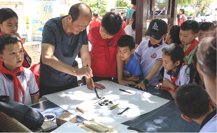 圖為黔西南州老年書畫研究會會員現場給同學們傳授講解書法。