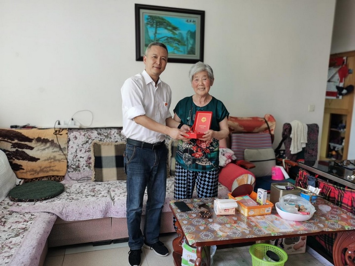 為金漫為張巧芝老黨員頒發“光榮在黨50年”紀念章。