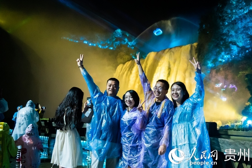 游客在夜間黃果樹前打卡拍照。人民網記者 涂敏攝