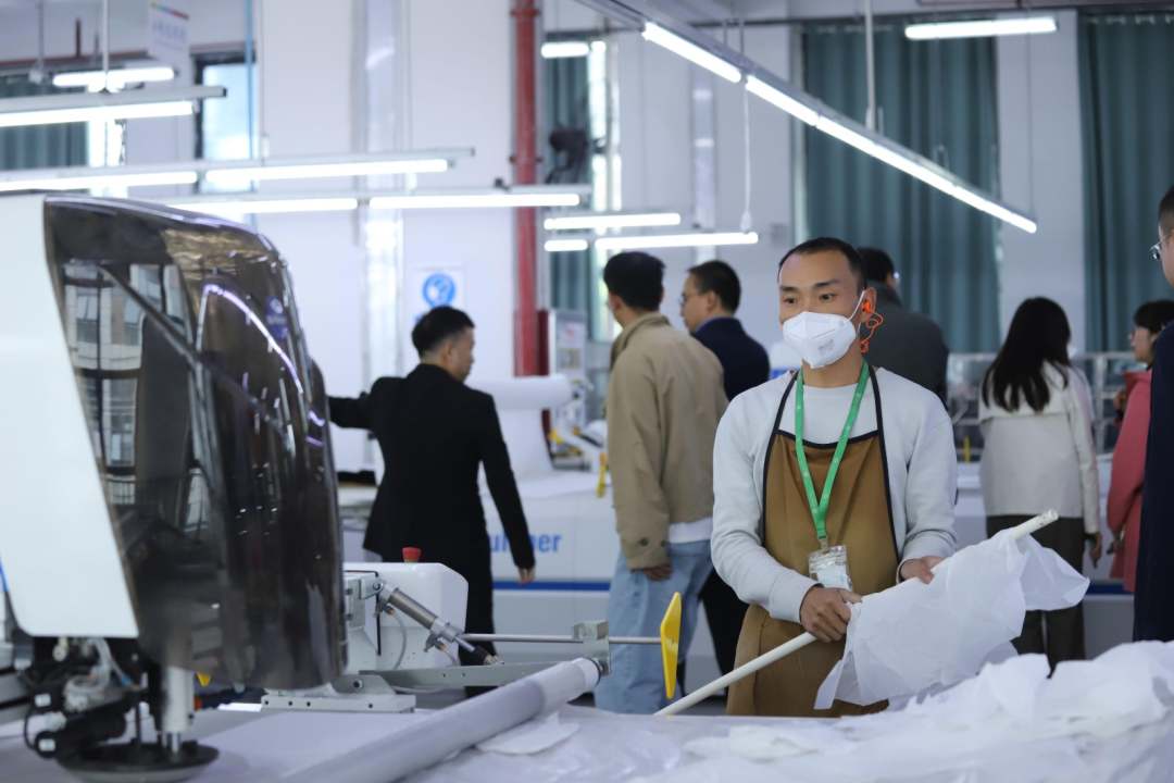  圖為工人操作機器裁剪布匹。