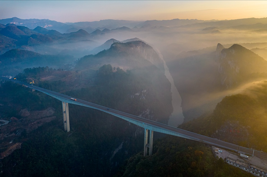 11月28日清晨，貴畢公路六廣河特大橋與云海、山川交相輝映，構成一幅壯美的交通畫卷。