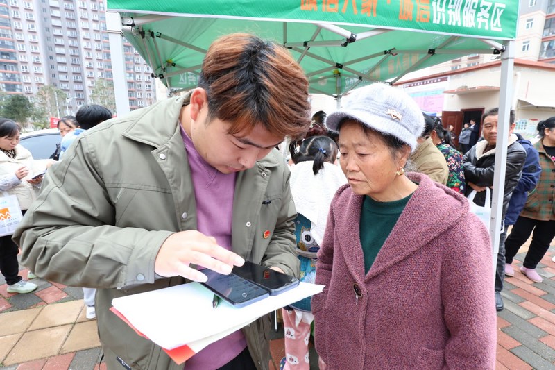 (3)2023年12月9日，清鎮市鄉愁社區云夢小鎮。圖為活動現場志愿者幫小區居民領取誠信消費券。（任芳靚 攝）.jpg