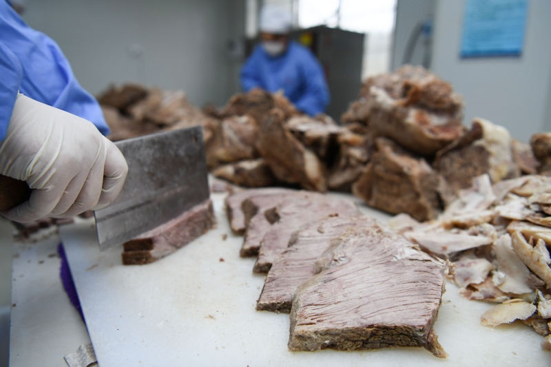工人正有序地切、炒、晾制牛肉干。