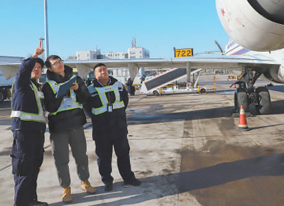 圖為邱超奕（中）在聽機務人員講解繞機檢查。