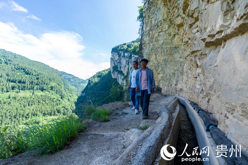 參與修建高流天渠的許光福老人和他的兒子許武君在巡查水渠。人民網記者 涂敏攝