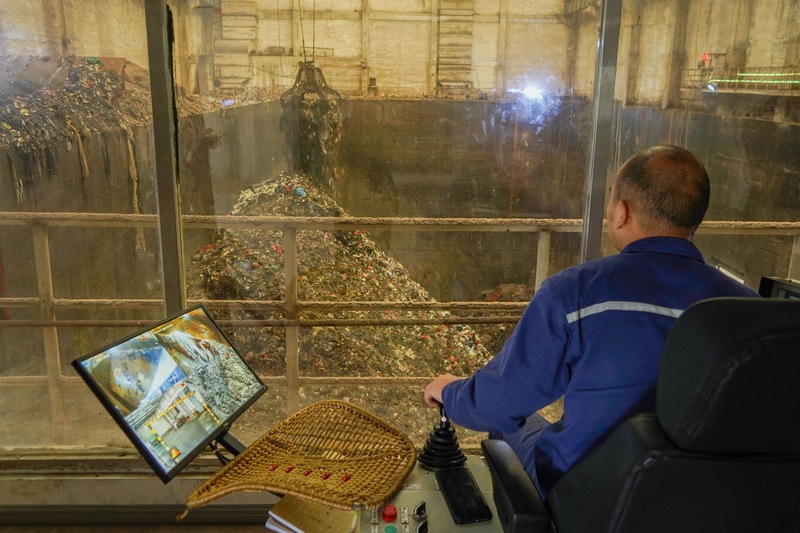 工作人員操作“鐵爪”從垃圾發酵坑中抓取垃圾投入焚燒爐。