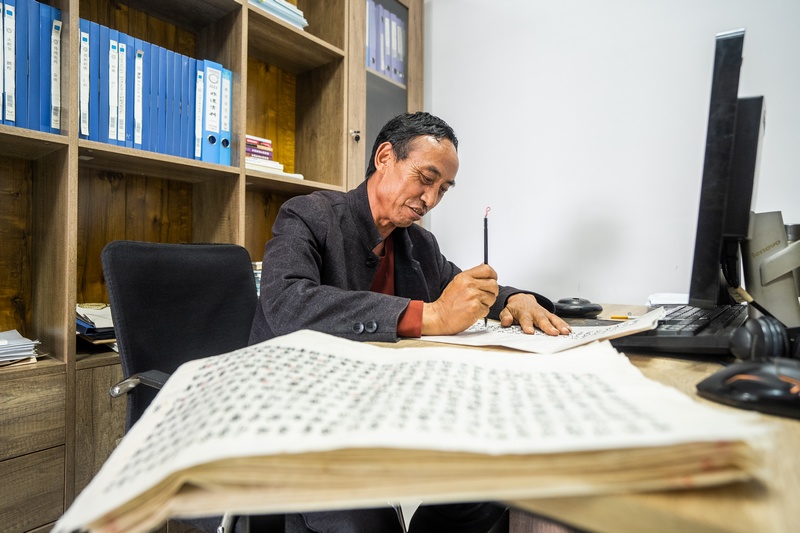 2024年7月5日，在貴州省畢節市百里杜鵑管理區，黃承龍正在辦公室抄寫彝族文獻資料。 