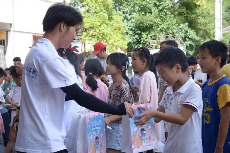 貴州輕工職業技術學院的志愿者給小朋友們發放禮物。