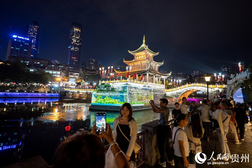 游客在甲秀樓激光投影前打卡拍照。人民網記者 涂敏攝