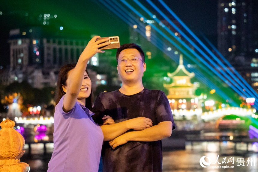 游客在甲秀樓景區音樂激光秀前打卡拍照。人民網記者 涂敏攝