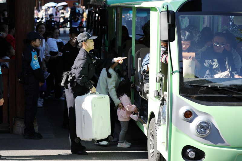 10月4日，雷山縣公安局輔警在西江千戶苗寨一號橋服務群眾乘坐觀光車。