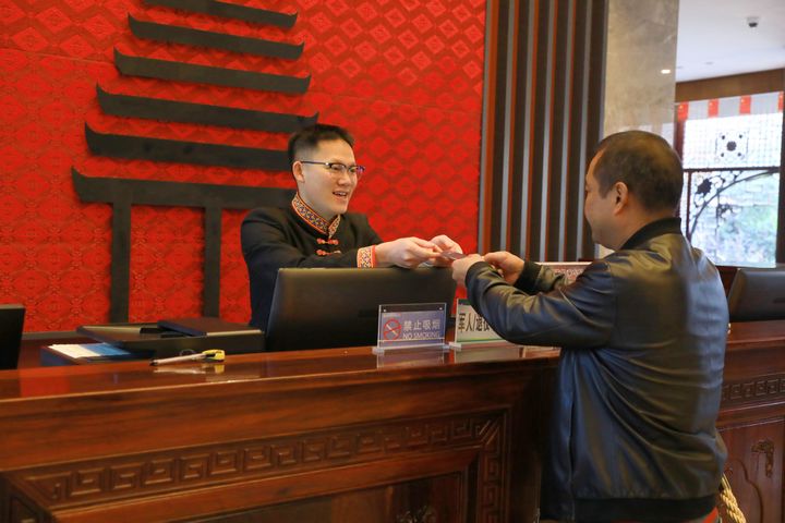 萬里將房卡遞給房客。楊潔茹攝