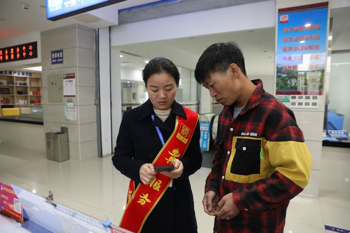 劍河縣政務服務中心工作人員正在幫助群眾手機線上操作業務辦理。
