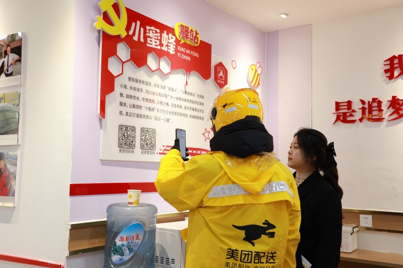 王涵（右）引導外賣小哥掃描流動黨員“歸隊碼”