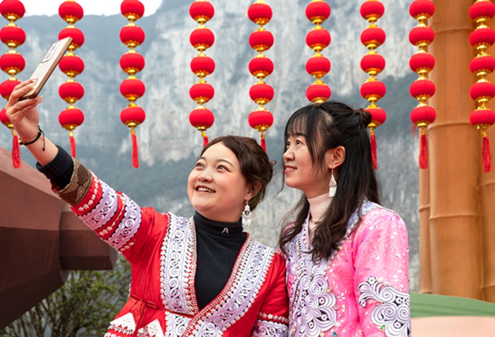 游客租用苗族服裝穿上在碼頭廣場自拍。