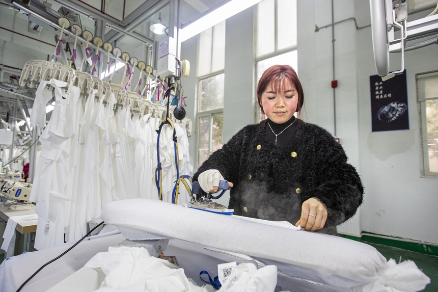2025年2月5日，工人在貴州省畢節市黔西市經濟開發區一家服飾企業車間熨燙服飾。