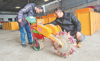 杜蘇林（右）在介紹新款電動式自動播種機。