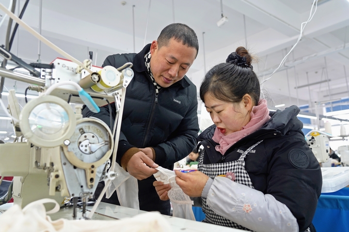 2025年2月25日，位于貴州省畢節市納雍縣工業園區的貴州博澤服裝有限公司生產車間，車間負責人與員工一起討論產品制作工藝。 楊英 攝.jpg