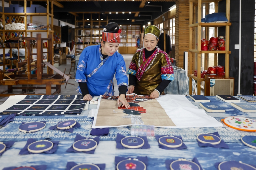 龍祿穎（右）與公司員工在手工刺繡車間交流苗繡新產品的設計理念。