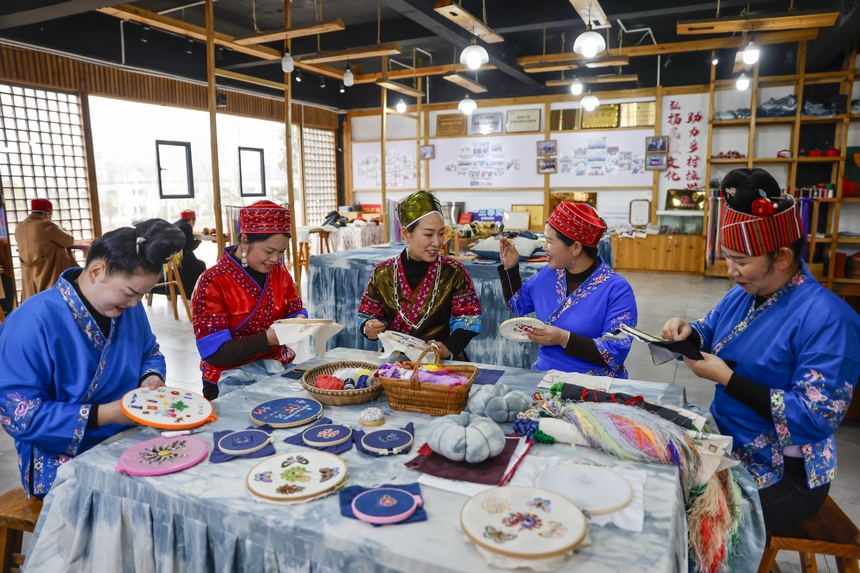 龍祿穎（中）與公司員工在手工刺繡車間刺繡。