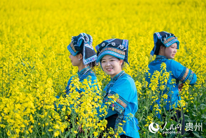 身著少數民族服飾的女孩在花田中拍照。人民網記者 涂敏攝