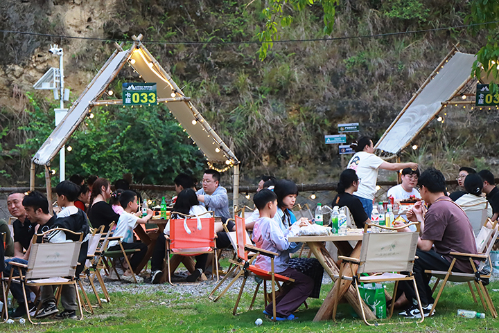 5、游客夜晚圍坐篝火旁，品嘗燒烤、仰望星空，沉浸于“時光音樂會”的民謠彈唱中。王琨榮攝