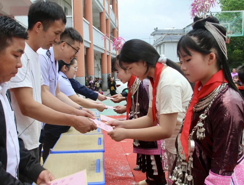 稅務干部向祥心村學生代表發放助學金和學習用品。