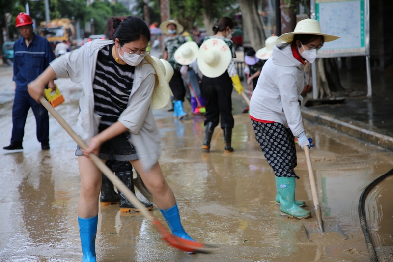 榕江縣稅務局第三黨支部書記蔣光慧在網格區域認真打掃淤泥。