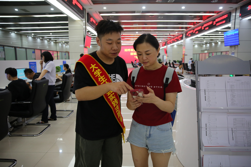 大學生志愿者輔導納稅人通過手機端電子稅務局開具發票。鄭婷攝