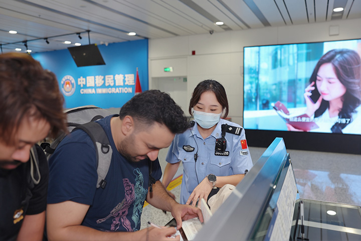 貴州邊檢總站執勤三隊隊長楊雨婕幫助入境外國籍旅客填寫入境卡。