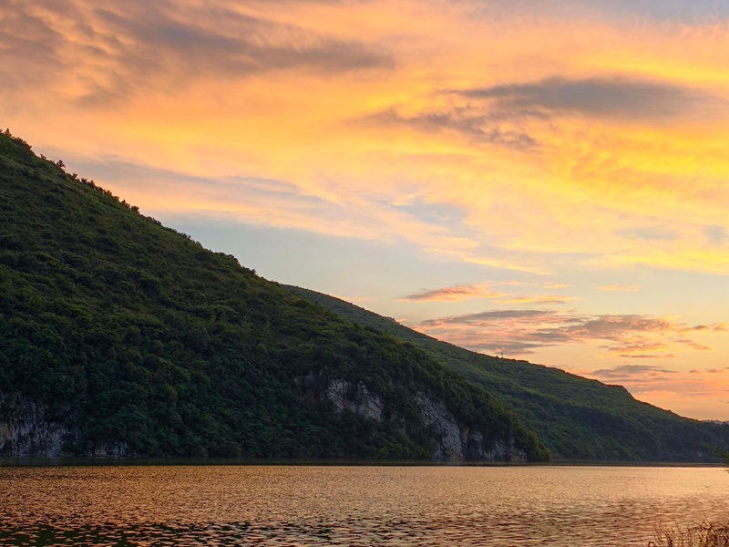 雨后的夾巖水庫空氣清新,落日余暉穿透云層,為天際染上橙紅、鎏金與淡紫的漸變色。張榮攝