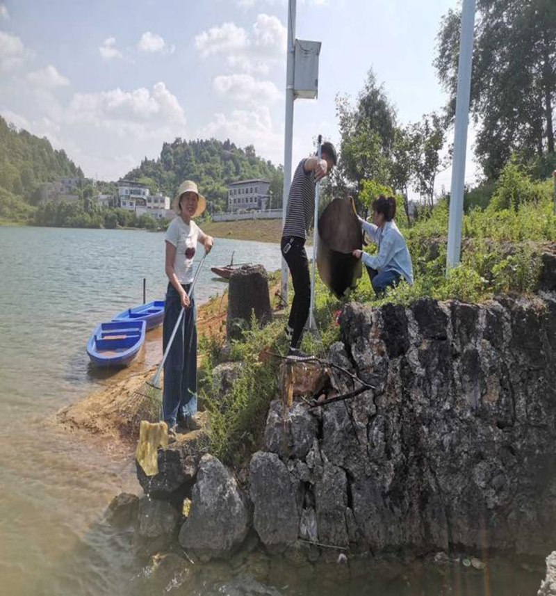 蘇流芳與駐村工作隊在湖面上清理垃圾。