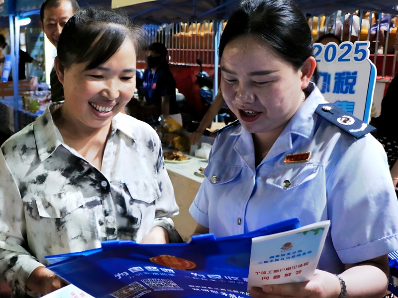稅務人員為群眾講解稅收政策并增送印有稅務二維碼的手提袋.jpg