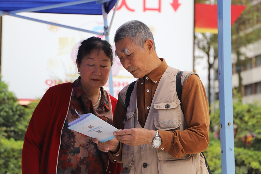 兩名游客正在認真閱讀《旅游安全實務手冊》。
